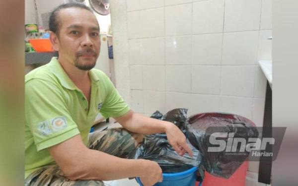 Mohd Rozlan menunjukkan baldi simpanan air yang disediakan di dapur rumahnya bagi tujuan memasak.