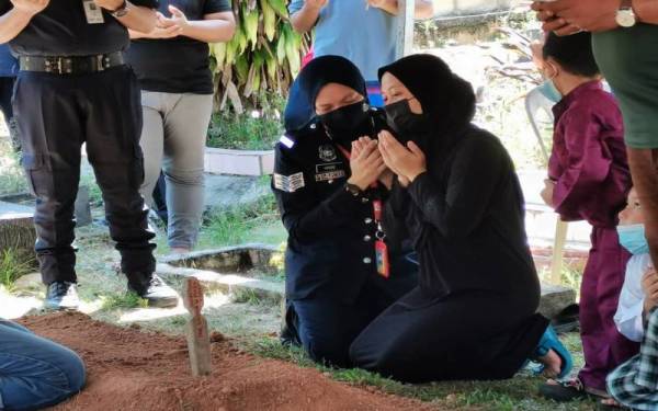 Ibu mangsa ditenangkan ketika menadah tangan berdoa di Tanah Perkuburan Islam Kampung Sendayan.