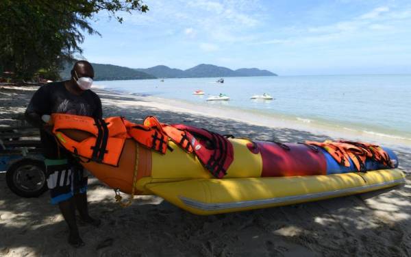 Budak pantai atau beach boy, Azmil Zulkifli Balakrishnan, 36, menyiapkan peralatan mainan laut di pantai Batu Ferringhi di sini sebagai persediaan menyambut pelancong pada hujung minggu ini.