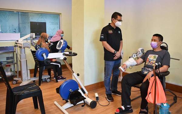 Mohd Zoolfaiz (dua, kanan) memantau fisioterapi yang dilakukan oleh pesakit. - Foto Bernama