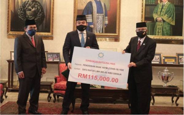 Abdul Aziz (kanan) menyerahkan replika cek kepada Tengku Amir sewaktu majlis yang berlangsung di Istana Mestika, pada Jumaat.