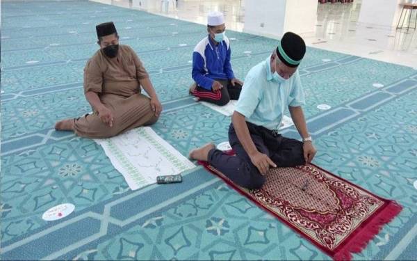 Dua jemaah lelaki mengambil kesempatan menggunakan sejadah pakai buang ketika mengerjakan solat.