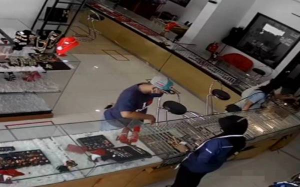 Suspek (kiri) ketika dirakam menunggu seorang pekerja mengira harga dua barang kemas.