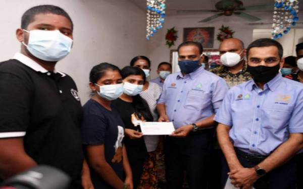Saravanan (dua dari kanan) menyampaikan bantuan Faedah Pengurusan Mayat (FPM) berjumlah RM2,000 dan faedah Perkeso sebanyak RM1,003.20 sebulan kepada anak-anak waris, S. Mahalatchumy, 19, (tiga, kiri), S Muthukumaran, 17, dan S. Kastury, 16, (dua, kiri) di kediamannya di Taman Sentosa pada Jumaat. - Foto Bernama