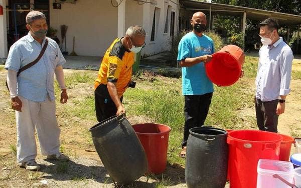 Jimmy Puah (kanan) membantu penduduk Kampung Sinaran, Kempas dan Kampung Maju Jaya yang terputus bekalan air di kawasan tersebut, pada Jumaat.