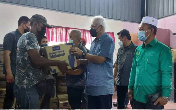 Hamzah (tiga dari kanan) menyampaikan kotak makanan kepada penduduk di Kampung Sungai Ara, Batu Kurau pada Sabtu.
