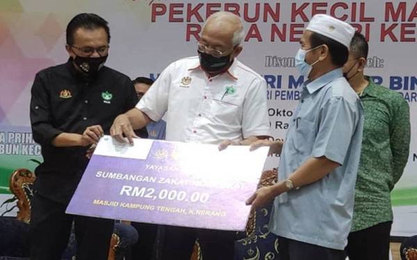 Mahdzir (dua kiri) menyerahkan sumbangan zakat korporat Yayasan Risda kepada wakil Masjid Kampung Tengah, Kuala Nerang pada Majlis Pekebun Kecil Makmur Risda Kedah, pada Sabtu.