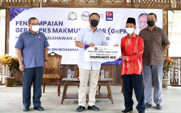 Hasni (tengah) menyampaikan geran kepada penerima, Daud Salam pada majlis Penyampaian Geran PKS Makmur Johor (GePKS) di Santai Homestay, Parit Archong, Pontian, pada Sabtu.