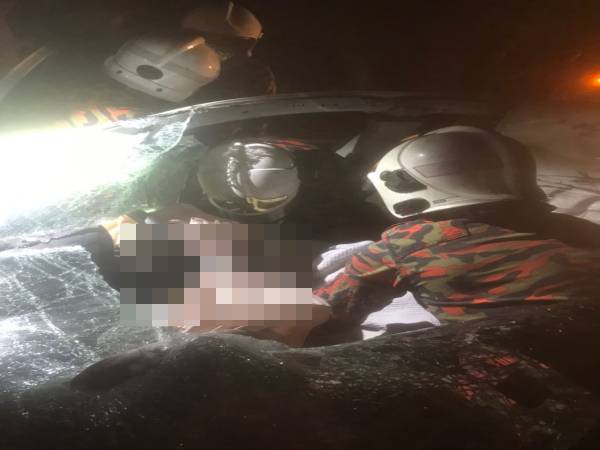 Anggota bomba membantu mengeluarkan seorang mangsa di bahagian tempat duduk pemandu dalam kemalangan di Jalan Pinang Hala Bukit Tongkat, Kluang pada malam Sabtu.