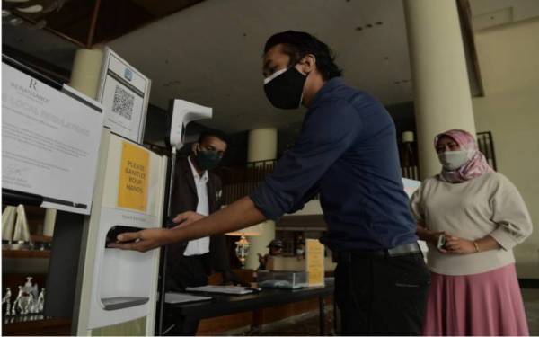 Orang ramai diwajibkan menunjukkan sijil yang telah lengkap divaksin dua dos dan perlu menggunakan cecair sanitasi yang disediakan sebelum dibenarkan masuk ke dalam sebuah hotel pada tinjauan baru-baru ini. - Foto Bernama
