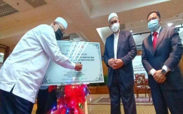 Ahmad (kiri) menurunkan tandatangan sebagai simbolik pelancaran Ringkasan Eksekutif Draf Rancangan Tempatan Jajahan Pasir Puteh 2035 di Dewan Teratai, Kota Darulnaim, Kota Bharu pada Isnin.