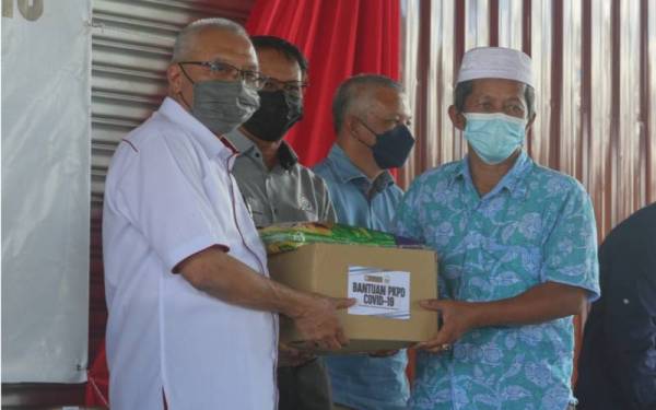 Zamri (kiri) menyerahkan sumbangan kepada setiap wakil unit sempena Majlis Menyampaikan Sumbangan PKPD Covid-19 di Pertubuhan Peladang Kawasan (PPK) Gerai, Besut.