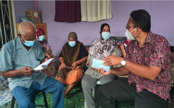 Mohd Rafiq ketika menziarahi sebuah keluarga di Kampung Tanah Merah, Krubong pada Selasa.