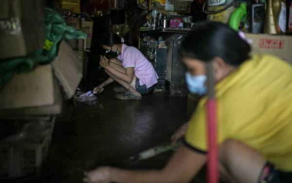 Anak pemilik kedai alat ganti dan servis motosikal, Lim Nee Pin, 30, membersihkan dkedainya yang dipenuhi lumpur selepas dilanda banjir kilat petang semalam ketika tinjauan foto Bernama di Yan hari ini.
