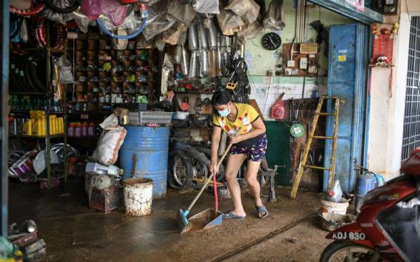Seorang pekerja kedai alat ganti dan servis motosikal sedang membersihkan kedainya yang dipenuhi lumpur selepas dilanda banjir kilat petang semalam ketika tinjauan foto Bernama di Yan hari ini.
