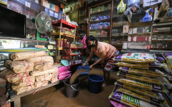 Pemilik kedai runcit Ooi Ah Khuah, 64, sedang membersihkan kedainya selepas dilanda banjir kilat petang semalam ketika tinjauan foto Bernama di sini, hari ini.

