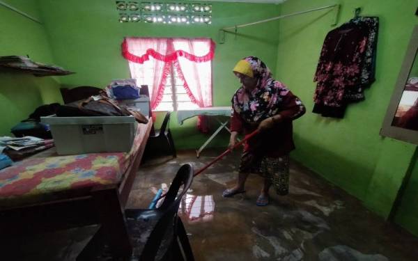 Zaleha sedang membersihkan bilik tidur dalam rumahnya di Kampung
Telok Mat Acheh di sini pada Khamis.