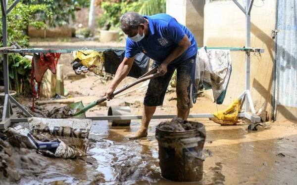  Amzaini Nayan, 59, membersihkan kawasan halaman rumahnya yang diselaputi lumpur akibat dilanda banjir kilat petang semalam, ketika tinjauan fotoBernama di Kampung Seberang Pekan, Yan hari ini. - Foto Bernama