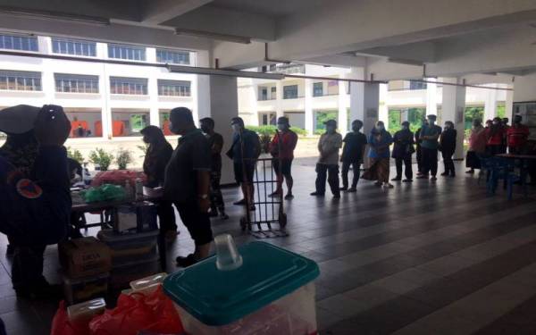 Sebahagian mangsa banjir di PPS SK Taman Merdeka beratur untuk mengambil makanan.