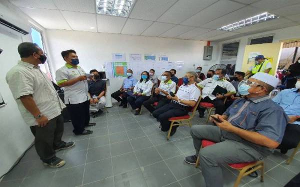 Mansor (duduk; dua dari kanan) mendengar taklimat mengenai Sungai Kereh ketika lawatan kerjanya di Pulau Pinang pada Sabtu.