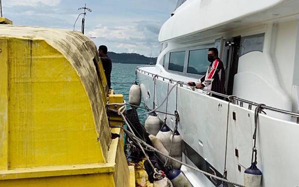 Bot persiaran (kanan) disyaki cuba memindahkan minyak kepada sebuah kapal kargo (kiri) di kedudukan 0.5 batu nautika, barat laut, Terminal Feri Penumpang, Langkawi pada Khamis. FOTO MARITIM MALAYSIA