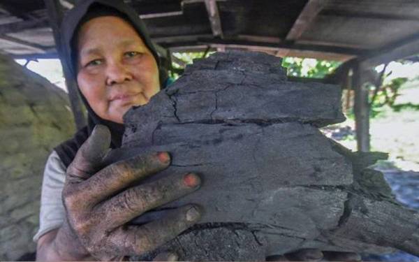 Pekerja arang Mariam Che Muda, 56, menunjukkan sebahagian arang yang sudah siap dibakar sebelum dibungkus ke dalam beg plastik ketika ditemui Bernama di Kampung Bukit Mak Lipah Mahligai baru-baru ini. - Foto Bernama