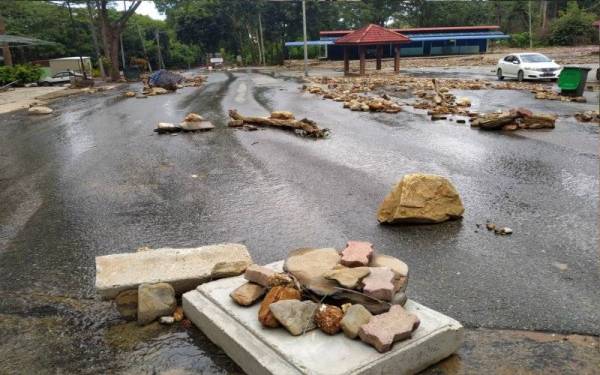 Serpihan batu yang dihanyutkan air deras jelas kelihatan di atas jalan tar di Dataran Titi Hayun menyebabkan kawasan itu tidak selamat dikunjungi.