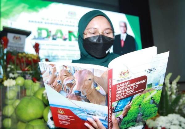 Siti Farhana Haron,32, melihat buku yang dilancarkan pada majlis pelancaran Dasar Agromakanan Negara 2021-2030 diadakan di Wisma Lembaga Pertubuhan Peladang. Foto Sinar Harian/Rosli Talib