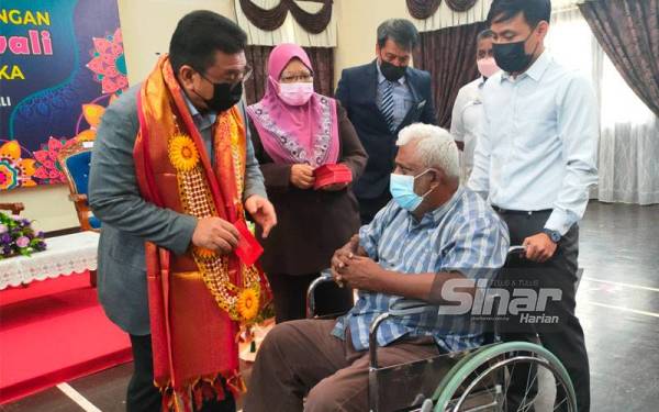 Sulaiman (kiri) ketika mnyampaikam sumbangan kepada seorang warga emas di Seri Bendahara, Ayer Keroh pada Isnin.