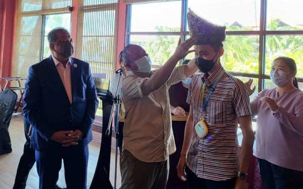 Jafry memakaikan Chong Wei sigah (tengkolok) sebagai simbolik pelantikan beliau menjadi duta pelancongan bagi negeri Sabah.