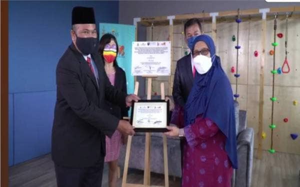 Siti Mariah (kanan) menyerahkan cenderahati kepada Zawawi (kiri) selepas majlis menandatangani kerjasama pintar itu pada Rabu.