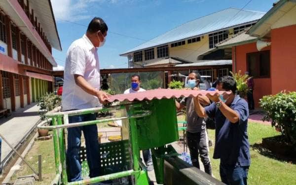 Mohamad Ali (kiri) melihat bumbung baharu yang hendak dibaiki di SK Kampung Gelam, Melaka pada Rabu.