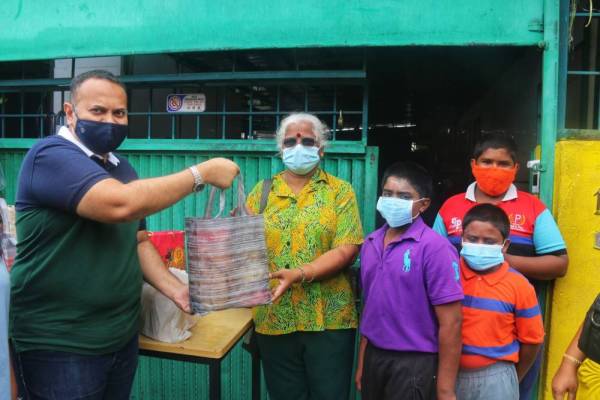 Sajahan (kiri) menyampaikan makanan dan barang keperluan kepada penerima di pekarangan Gurumatha Ashram, Sungai Petani pada Rabu.