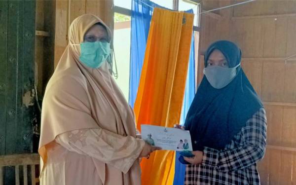 Wan Sazatul Azma (kanan) menerima sumbangan daripada Rohani yang hadir ke rumahnya mewakili kerajaan negeri pada Khamis.