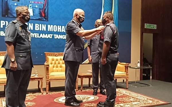 Mohammad Hamdan (tengah) memakaikan pingat kebesaran jabatan kepada anggota bomba di Johor Bahru.