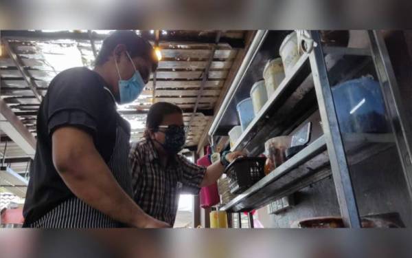 Noorzanarudin Syah (kanan) dan pembantu restoran, Mohd Zulhilmie Zabidi, 32, tidak ketinggalan melihat pembentangan Bajet 2022 melalui telefon pintar di restoran tersebut pada Jumaat.