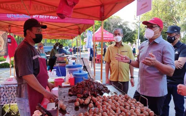 Dari kanan: Izham dan Abd Hamid ketika melawat peniaga di tapak Selangor Agro Market di Taman Tasik Cyberjaya, di sini pada Sabtu.