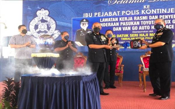 Mazlan (kanan) menyerahkan replika kunci kepada Shafien sebagai simbolik penyerahan 34 kenderaan PDRM di IPK Kelantan, Kota Bharu pada Ahad.