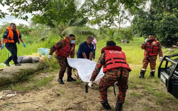 Anggota bomba membawa naik mayat yang ditemui tersangkut pada pokok di tepi sungai berhampiran Jeti Nelayan Kampung Ulu Pulai pada Isnin.