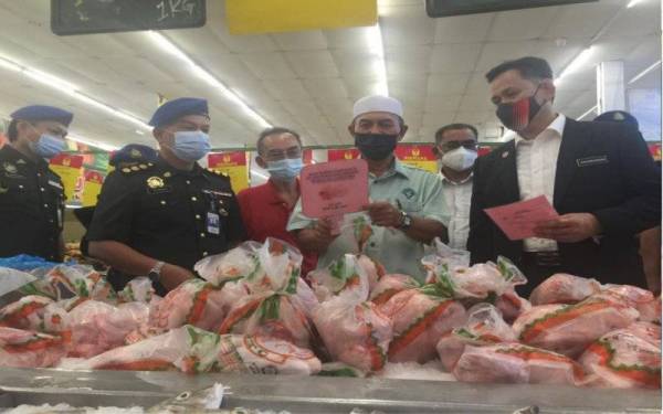 Saharuddin (kanan) bersama Wan Hapandi (dua dari kanan) melihat harga ayam yang tersenarai dalam SHMMP Deepavali di sebuah pasar raya di Kuala Dungun pada Isnin.