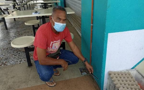 Abdul Razak menunjukkan kesan paras limpahan air laut akibat daripada fenomena air pasang besar pada tahun lalu di kawasan medan selera Kukup.