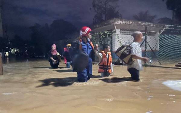 Anggota APM sedang memindahkan penduduk terjejas banjir di Taman Murai jaya Durian Tunggal pada malam Isnin.
