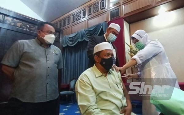 Dr Izani (berdiri dua dari kanan) memberikan sokongan kepada Exco Pembangunan Belia, Sukan dan Badan Bukan Kerajaan (NGO) Kelantan, Wan Roslan Wan Hamat yang menerima suntikan dos penggalak vaksinasi Covid-19 di Kota Darulnaim, Kota Bharu pada Selasa.