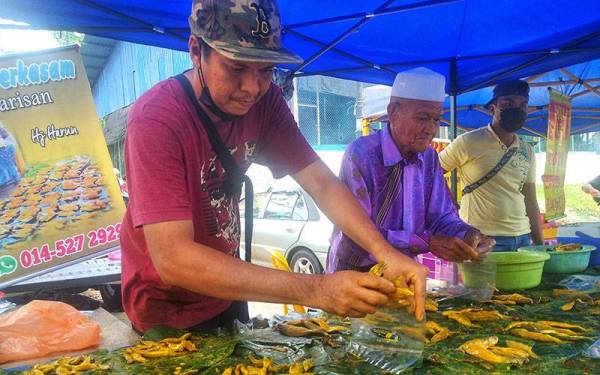 Ridzuan bersama bapanya dengan ikan pekasam yang dihasilkan dan mendapat sambutan pelanggan di Pekan Sehari Temerloh.