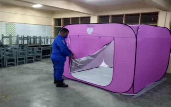 Anggota Angkatan Pertahanan Awam (APM) memasang khemah untuk menempatkan mangsa banjir di PPS Melayu Raya, Pontian pada malam Selasa.