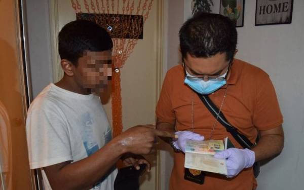 Anggota serbuan memeriksa dokumen milik suspek (kiri). 