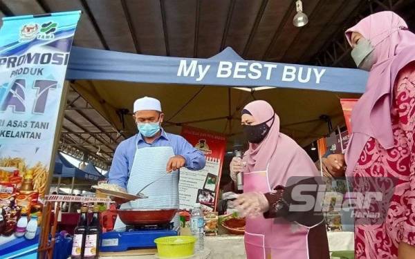 Tuan Mohd Saripudin (kiri) menunjukkan demostrasi memasak sempena merasmikan pembukaan semula My Best Buy di Pusat Tranformasi Luar Bandar (RTC) Tunjong pada Jumaat.