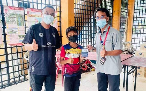 Mohamad Nasir (kanan) menyerahkan MyKad kepada salah seorang murid Sekolah Kebangsaan Pulau Perhentian, Besut.