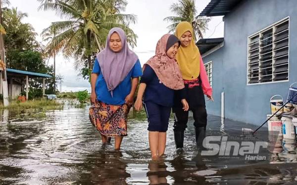 Beberapa penduduk sedang bermain air banjir di Kampung Alor Gelegah pada Jumaat.