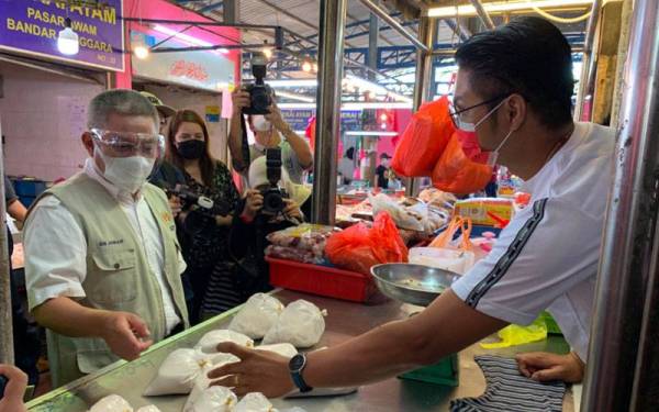 Dr Adham (kiri) ketika melawat gerai jualan di Pasar Awam Bandar Tenggara di Kota Tinggi pada Sabtu.